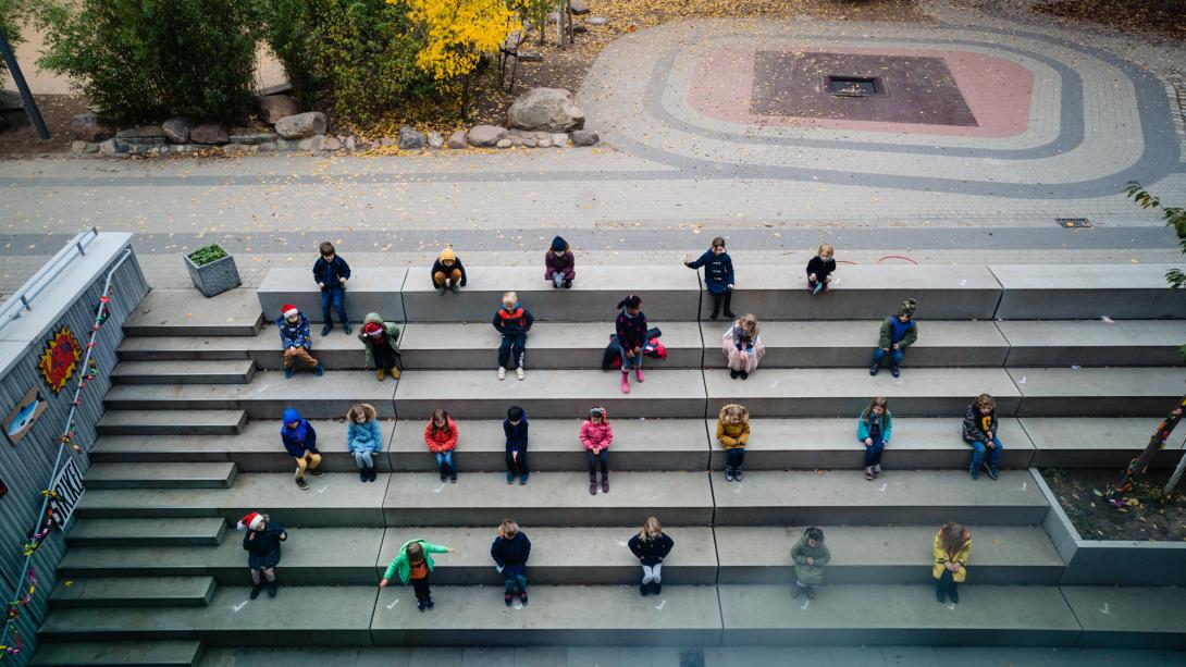 Primary students sitting on steps, preparing for a winter concert
