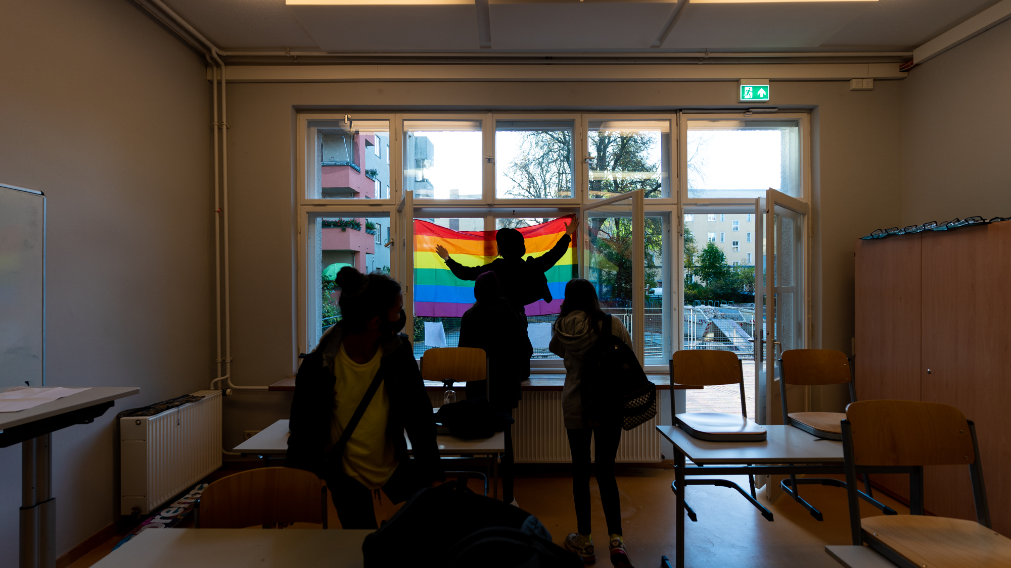 Secondary students attaching rainbow flag to window